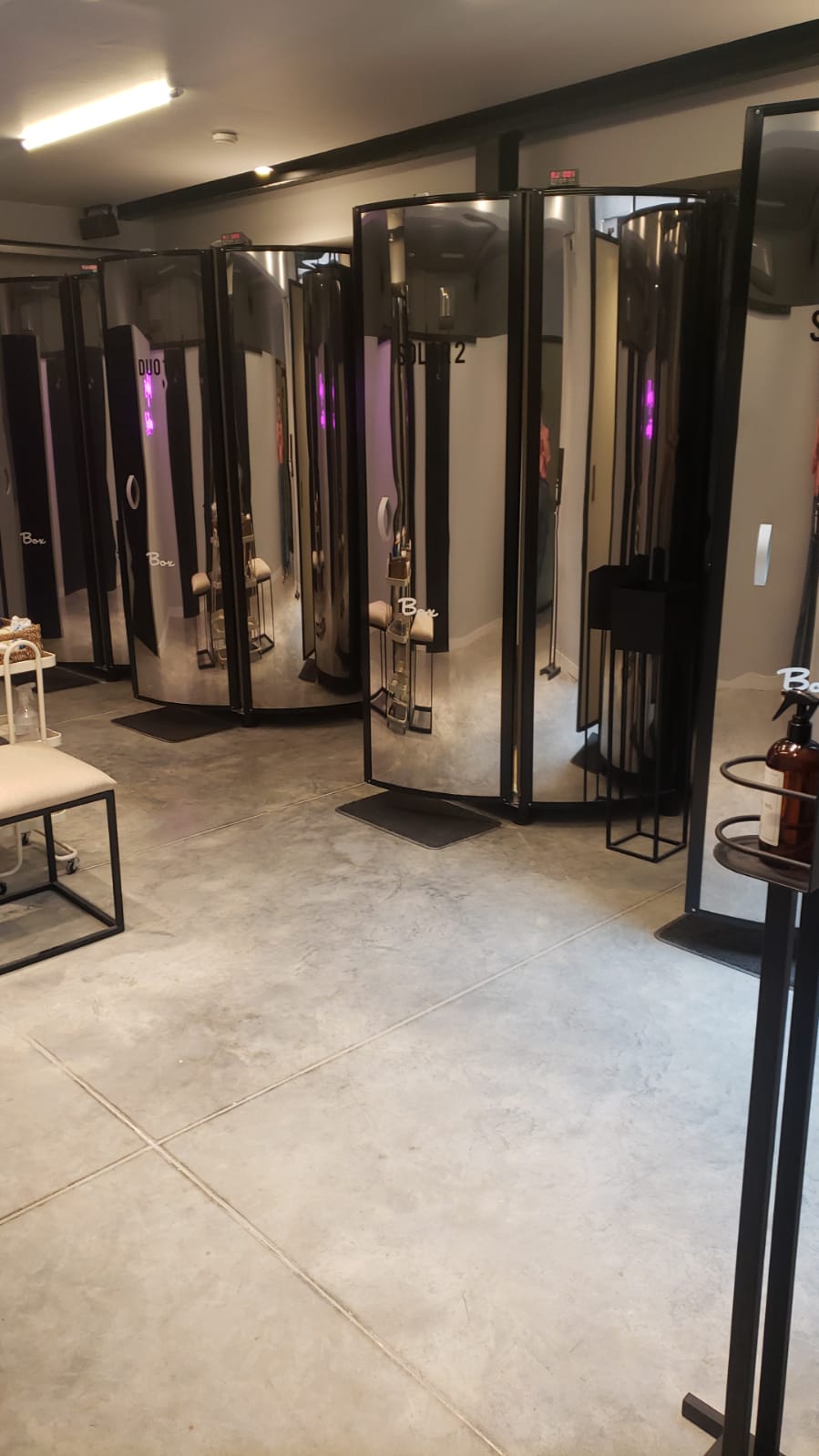 Close-up aesthetic of modern luxury skincare beauty treatment room, warm mood lighting, dark elegant vanity with organic botanical serums, fluffy folded towels, warm golden glow, serene spa aesthetic.